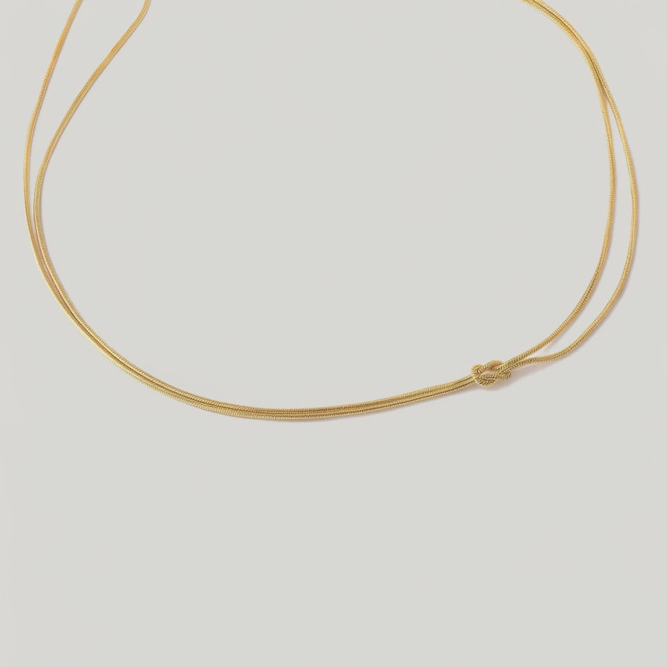 video of a gold-plated choker necklace with a simple infinity symbol design