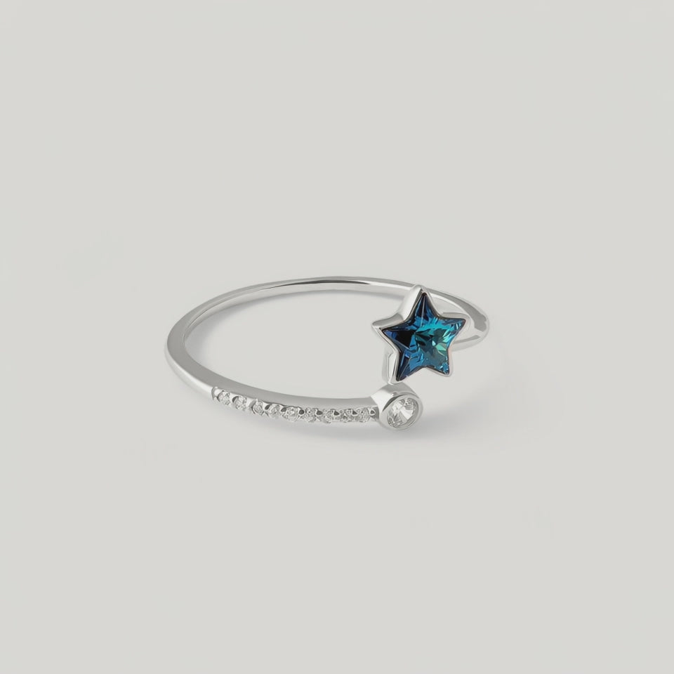 video showing a sterling silver ring with a blue topaz star in the center, surrounded by smaller sparkling gemstones on the band