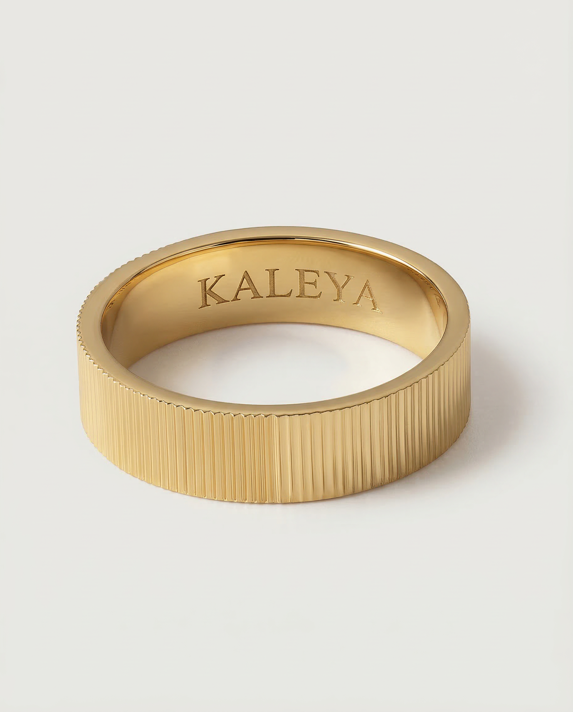 A gold plated band ring with a ribbed texture, displayed on a white background.