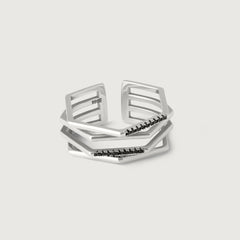 A silver ring with a hexagonal design featuring geometric flowing lines and black crystal accents on the edges.