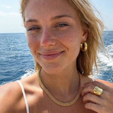 Woman with blonde hair and gold jewelry by the ocean