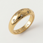 A gold-plated ring with a smooth, domed surface adorned with five star-shaped bezels containing crystals.