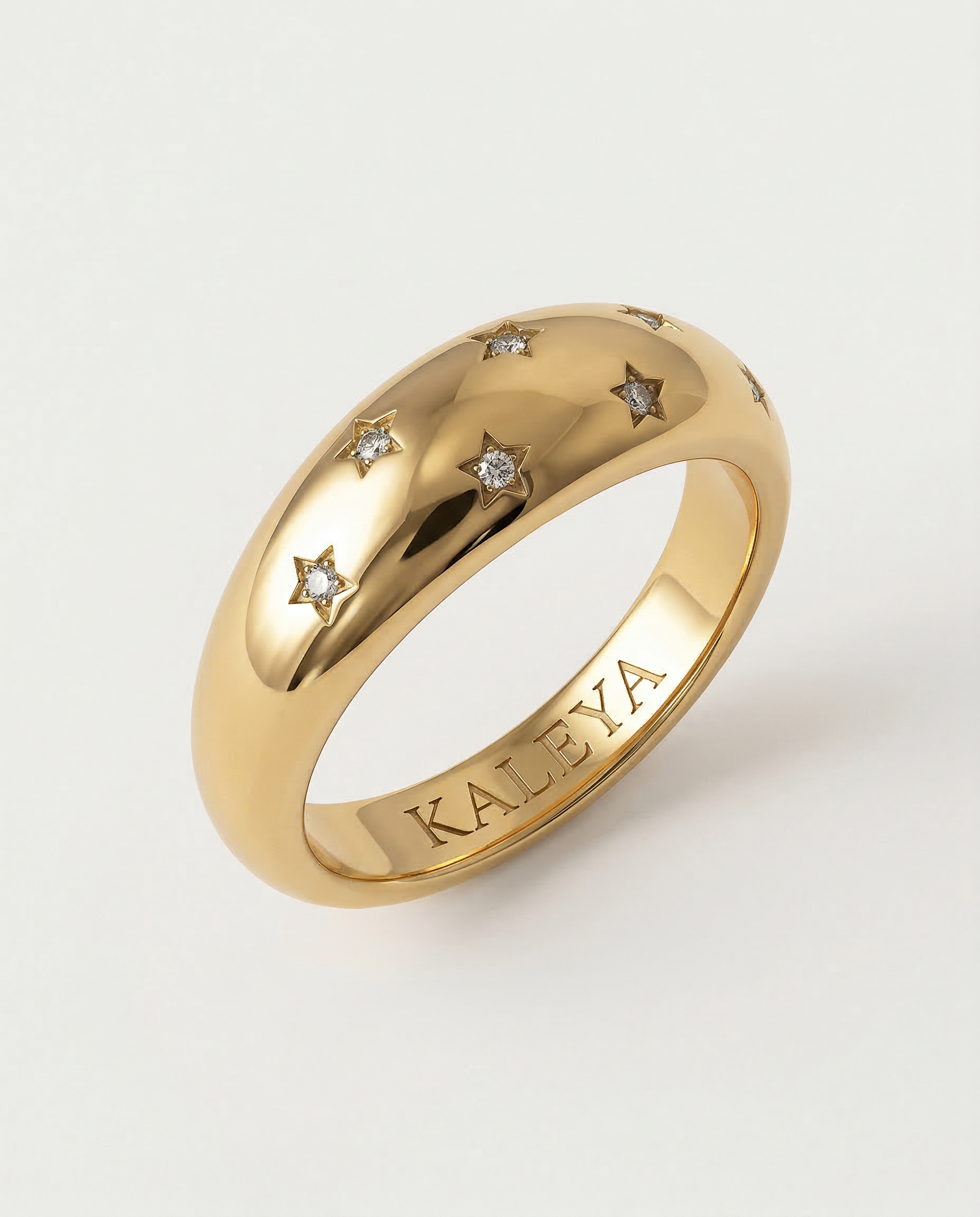 A gold-plated ring with a smooth, domed surface adorned with five star-shaped bezels containing crystals.